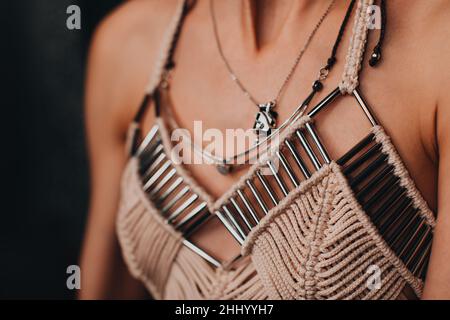 Partie d'un corps féminin vêtu d'un élégant haut de boho beige avec des détails argentés.Mode et accessoires pour femmes Banque D'Images