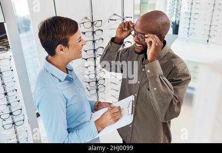 Ils s'adaptent parfaitement.Photo d'un optométriste aidant un jeune homme à choisir une nouvelle paire de lunettes. Banque D'Images