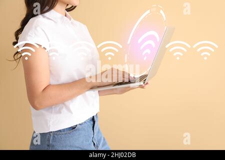 Jeune femme avec ordinateur portable utilisant le wi-fi sur fond de couleur Banque D'Images