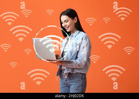 Jeune femme avec ordinateur portable utilisant le wi-fi sur fond de couleur Banque D'Images