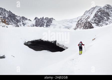 Tourisme avec sac à dos près de la grotte de glace au glacier dans un magnifique paysage de vallée de montagne couverte de neige à Almaty, Kazakhstan Banque D'Images