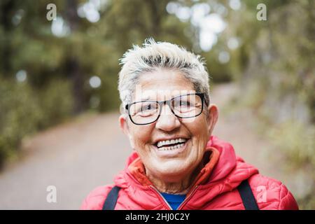 Portrait de la femme hispanique senior ayant du plaisir pendant la journée de trekking dans la forêt de montagne - Focus sur le visage Banque D'Images