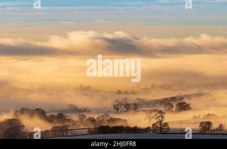 La flèche de l'église All Saints Church, l'église paroissiale de Burton à Lonsdale, dans le North Yorkshire, s'élance au-dessus d'une spectaculaire inversion de nuages à la fin de l'af Banque D'Images