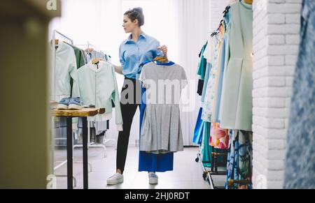 Femme concentrée cueillant des vêtements dans l'atelier Banque D'Images