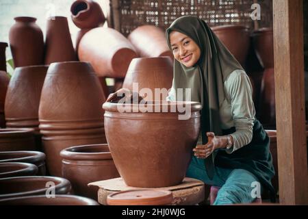 jeune femme souriante dans un foulard assis entre la poterie Banque D'Images