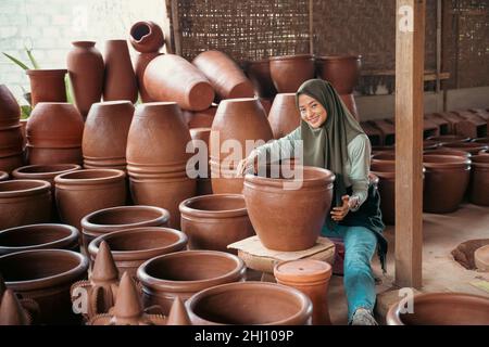 jeune femme souriante dans un foulard assis entre la poterie Banque D'Images