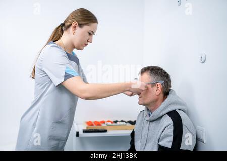 Le patient masculin subit un test oculaire et une prescription de lunettes en clinique d'ophtalmologie.Optométriste vérifiant la vue et la vision du patient Banque D'Images