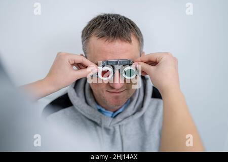 Le patient masculin subit un test oculaire et une prescription de lunettes en clinique d'ophtalmologie.Optométriste vérifiant la vue et la vision du patient Banque D'Images