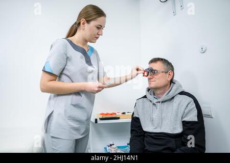 Le patient masculin subit un test oculaire et une prescription de lunettes en clinique d'ophtalmologie.Optométriste vérifiant la vue et la vision du patient Banque D'Images