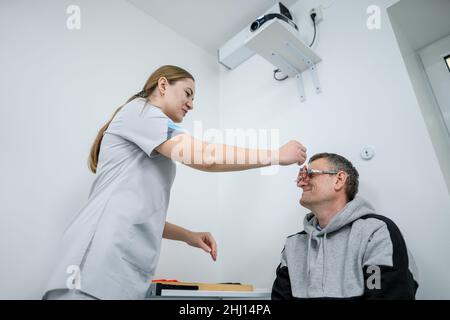 Le patient masculin subit un test oculaire et une prescription de lunettes en clinique d'ophtalmologie.Optométriste vérifiant la vue et la vision du patient Banque D'Images