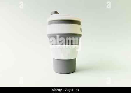 Tasse en silicone réutilisable pour café à la main sur fond blanc. Banque D'Images