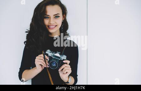 Jeune brunette debout sur fond blanc avec appareil photo Banque D'Images