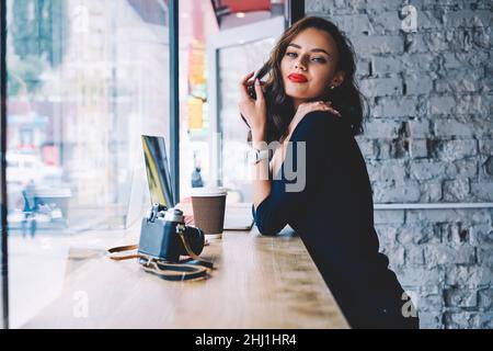 Une jeune femme positive boit du café chaud en se tenant à la cafétéria Banque D'Images