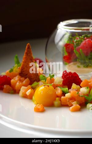 Un apéritif dans un restaurant gastronomique, tartare de saumon du chef avec framboises et jaune d'œuf Banque D'Images