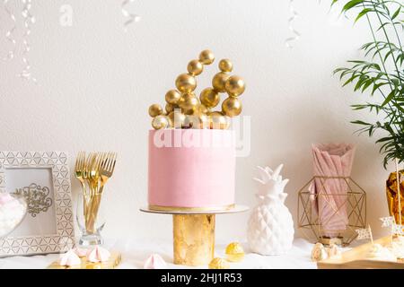 Table d'anniversaire des fêtes avec gâteau et ballons.Décoration rose et dorée Banque D'Images