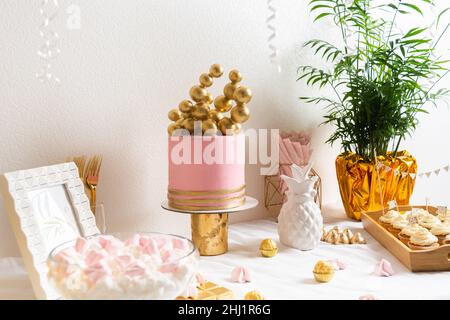 Table d'anniversaire des fêtes avec gâteau et ballons.Décoration rose et dorée Banque D'Images