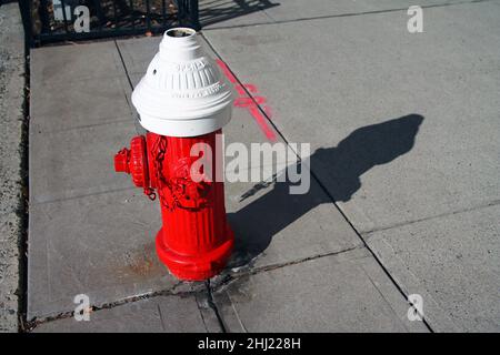 Une borne d'eau traditionnelle rouge et blanche sur un sentier en béton en plein air par une journée ensoleillée Banque D'Images