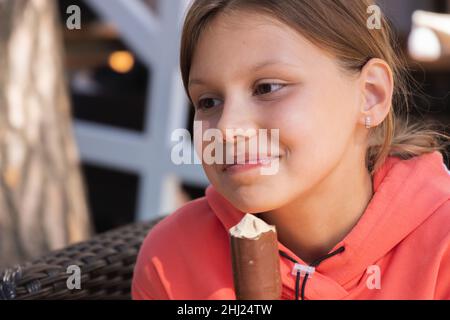 Bonne petite fille à capuche rouge mange une crème glacée, portrait en gros plan avec une mise au point sélective Banque D'Images