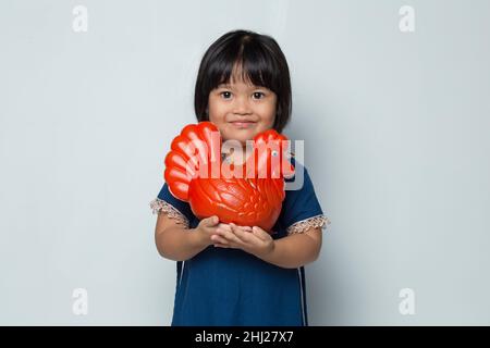 bonne petite fille asiatique économiser de l'argent avec une banque de poulet isolée sur fond blanc Banque D'Images