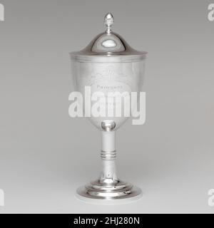 Coupe de vin ca.1800 Joseph Foster à la fin du XVIIIe siècle, la coupe à vin traditionnelle en forme de cloche sur tige de balster avait évolué en un modèle encore plus restreint.Ici, le corps ovoïde, l'ornement côtelé horizontal et la gravure brillante reflètent l'idiome néoclassique.De grandes tiges cylindriques sur des bases circulaires étalées et des couvercles bombés avec des embouts en corne accentuent la verticalité et la dignité de ce navire et de son compagnon (33.120.232a, b), qui ont été fabriqués vers 1800 pour l'église de Bratle Street à Boston.La marque de Joseph Foster, le fabricant de la paire, apparaît sur une quantité considérable de Bos Banque D'Images