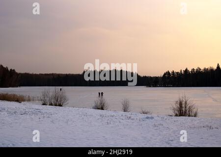 Lac couvert de neige sous la glace au coucher du soleil Banque D'Images