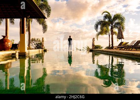 Un homme debout au bord de la piscine à débordement Banque D'Images