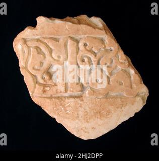 Fragment d'un panneau de Dado sculpté et peint 10th–11th siècle ce fragment d'un panneau sculpté a été fouillé en 1939 dans une salle de Vineyard Tepe à Nishapur, ainsi qu'en 40.170.672.Les quelques lettres restantes de l'inscription peuvent être lues comme '[al-s](a)mawat wa['l-ard]', comme dans le verset Qur'anique (24:35) décrivant Dieu comme la lumière des cieux et de la Terre, qui se reproduit dans les inscriptions sur l'architecture des 11th et 12th siècles.Des traces de pigment dans la bande épigraphique suggèrent que les lettres auraient été placées contre un fond bleu, créant un effet frappant dans son cadre d'origine.Le maçon qui c Banque D'Images