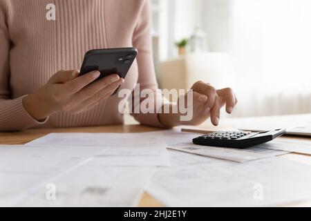 Woman effectue des calculs et paie des factures via l'application e-Bank sur smartphone Banque D'Images