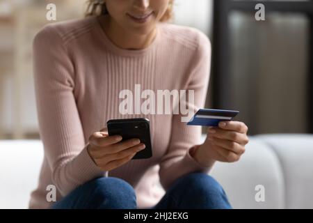 Femme facilite le paiement électronique à distance à l'aide d'un smartphone et d'une carte de crédit Banque D'Images