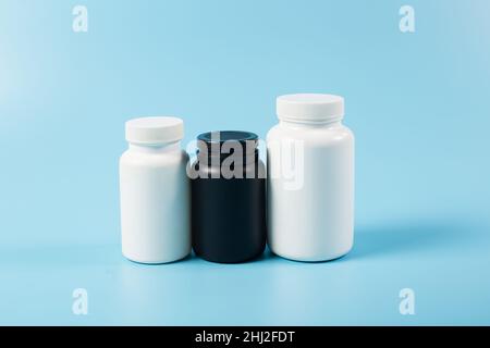 Récipients blancs et noirs avec blanc pour médicaments, gros plan sur fond bleu. Banque D'Images