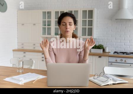 Femme assis près d'un ordinateur portable fait des exercices calmants pour réduire le stress Banque D'Images