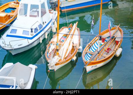 Les grands et petits bateaux amarrés se reflètent dans l'eau claire de la mer Méditerranée au port de pêche local dans la ville balnéaire le jour ensoleillé en été Banque D'Images