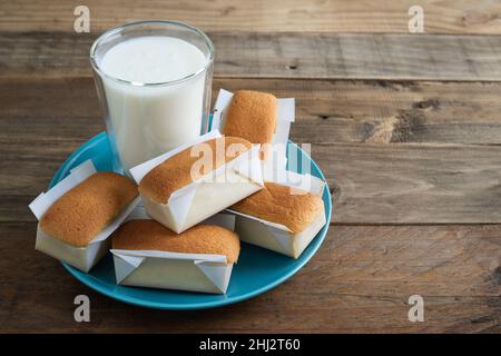 Mantecadas dessert typiquement espagnol.Petits gâteaux avec assiette bleue et verre de lait sur fond de bois.Copier l'espace. Banque D'Images