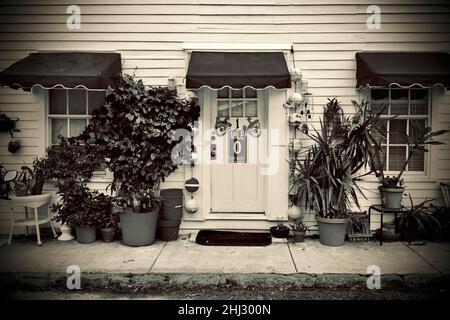 Porte avant avec marqueur de distance “0” et geckos décoratifs à Key West, Floride, FL, États-Unis.Des bouées de pêche suspendues et un auvent rouge entourent la porte. Banque D'Images