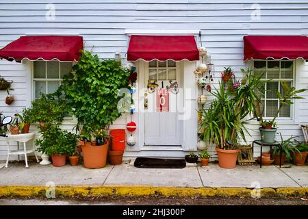 Porte avant avec marqueur de distance “0” et geckos décoratifs à Key West, Floride, FL, États-Unis.Des bouées de pêche suspendues et un auvent rouge entourent la porte. Banque D'Images