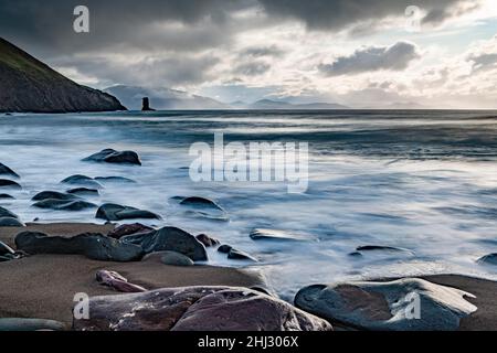 Plage de sable avec des pierres sur l'Atlantique Nord avec affleurement rocheux et ciel nuageux, péninsule de Dingle, Kerry, Irlande Banque D'Images