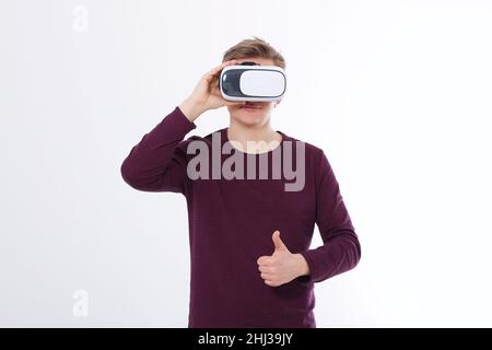 Jeune homme en réalité virtuelle lunettes isolées sur fond blanc et grand pouce vers le haut.Concept VR.Modèle et chemise vierge.Copier l'espace et la maquette Banque D'Images