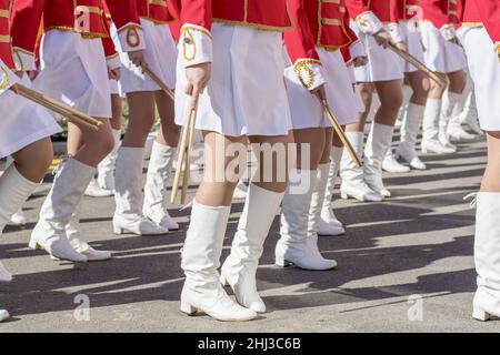 Groupe de jeunes filles en costumes de cérémonie brillants sont en marche dans la formation égale sur les rues de ville. Banque D'Images