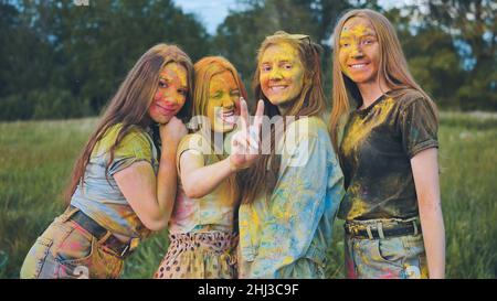 Filles gaies posant étalées dans de la poudre multicolore. Banque D'Images