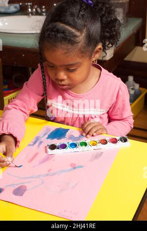 Éducation préscolaire 3-4 ans activité artistique fille peinture avec des couleurs d'eau Banque D'Images