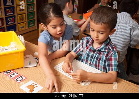 Éducation préscolaire 4-5 ans jeune fille et garçon jouant un jeu éducatif avec des lettres de l'alphabet Banque D'Images