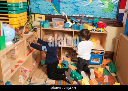 Éducation préscolaire 4 ans deux garçons nettoyant la zone du bloc, mettant des blocs loin Banque D'Images