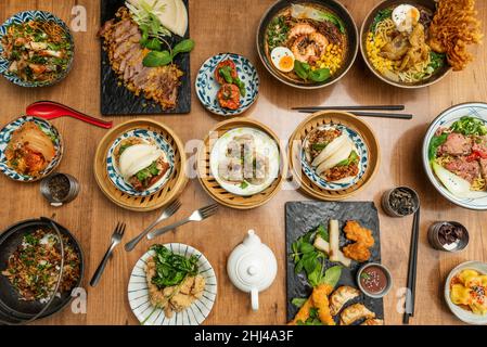 Ensemble de plats asiatiques, avec gyozas frits, boulettes, sauce soja, crevettes et crevettes,assortiment d'algues, de baguettes, de pain de bao, de canard croustillant et de kimchi Banque D'Images