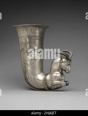 Rhyton se terminant dans la partie avant d'un vérin ca.5th Century B.C. Achaemenid ce navire argenté est appelé un «rhyton» (du rhéo grec, signifiant «passage») par les chercheurs parce qu'il a un bec au fond.Comme beaucoup de rhyta, il se compose d'un bécher en forme de corne et d'un élément sculptural creux, en l'occurrence sous la forme des parties avant d'un bélier à genoux ou d'un ibex.L'ibex a des cornes courbées, des oreilles pointues, des sourcils épais, un museau étroit et une barbe de menton.Des lignes de boucles en spirale sur la poitrine et le dos indiquent des cheveux ou éventuellement de la polaire.Les quartiers arrière de l'animal sont représentés en relief de rangée sur le bécher Banque D'Images