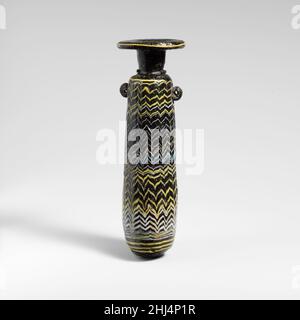 Verre alabastron (flacon de parfum) fin 4th–début 3rd siècle C.-B. Méditerranée orientale ou italien translucide vert très foncé (?), apparaissant noir opaque, avec poignées de la même couleur; traces en jaune opaque, blanc opaque et bleu turquoise opaque.disque à large rebord horizontal, avec bord arrondi épais; col cylindrique haut, effilée vers le bas; épaulement arrondi inégal;corps cylindrique à côtés droits,légèrement effilé vers le haut ; fond convexe inégal avec repères d'outillage et lissé dans un blob appliqué de verre de la même couleur ; sous l'épaulement, deux poignées verticales en anneau, l'une légèrement plus haute que l'autre, app Banque D'Images
