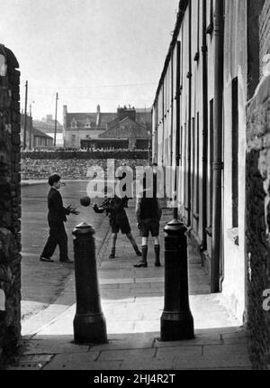 Newtown était une zone résidentielle de Cardiff, au pays de Galles, qui existait du milieu du XIXe siècle jusqu'à sa démolition en 1970.Sur la photo, les seuls véhicules qui passent sont les camions de chemin de fer qui s'envoûtent à la fin et donc la rue fait un terrain sûr pour un jeu de football.28th mars 1956. Banque D'Images