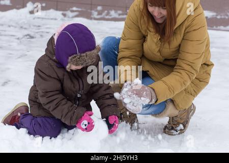 Mère et enfant jouant avec la neige faisant des boules de neige dans le parc d'hiver Banque D'Images