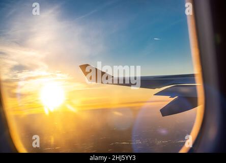 Vol et voyage, vue depuis la fenêtre de l'avion sur l'aile à l'heure du coucher du soleil.Aile de l'avion sous la terre et les nuages.Voyages, tourisme, vacances, semaine Banque D'Images