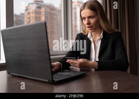 Focalisée femme caucasienne shopping en ligne avec ordinateur portable et carte de crédit, femme d'affaires payant pour une commande dans le bureau, la commande de marchandises sur l'Internet Banque D'Images