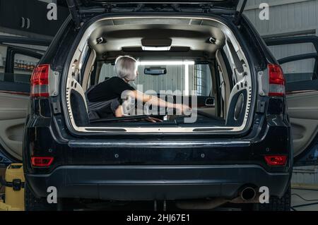 Femme travailleuse aspirant poussière intérieur de la voiture dans le lave-auto. Banque D'Images